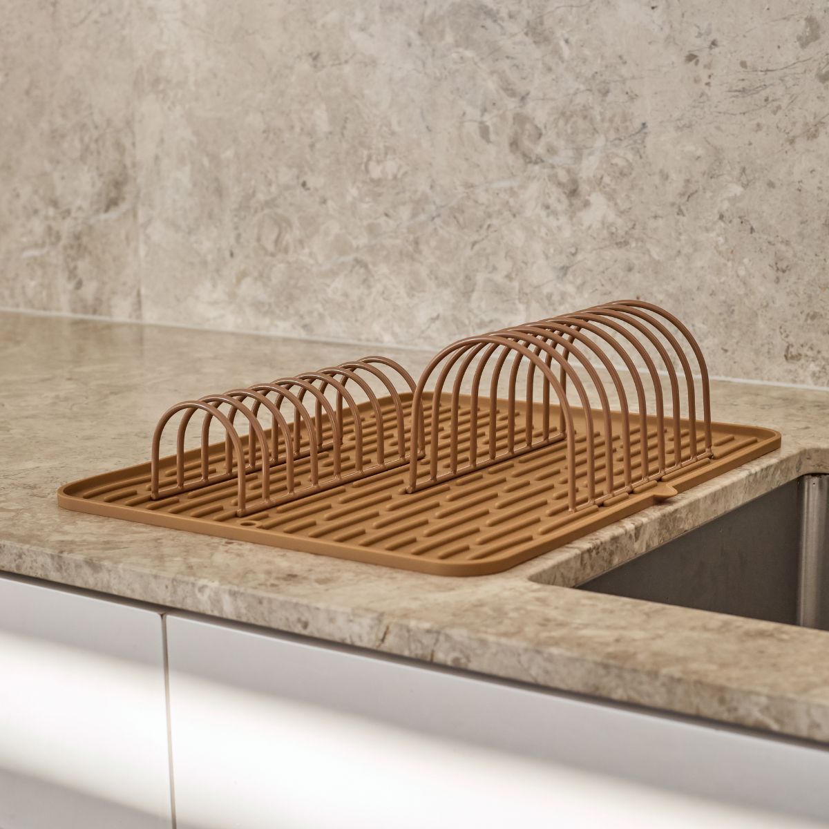 Brown dish rack on a kitchen counter with a neutral background